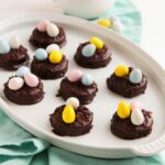 oval platter filled with chocolate covered oreos topped with chocolate sprinkles and mini chocolate eggs