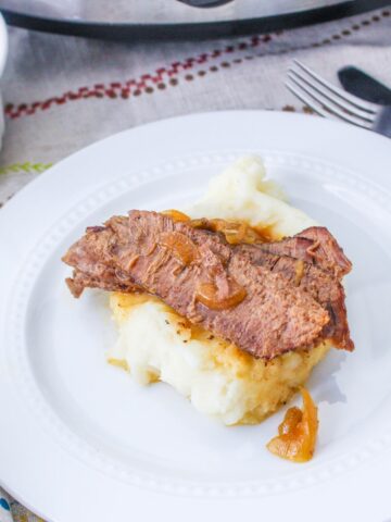 slices of flank steak and onions served over mashed potatoes