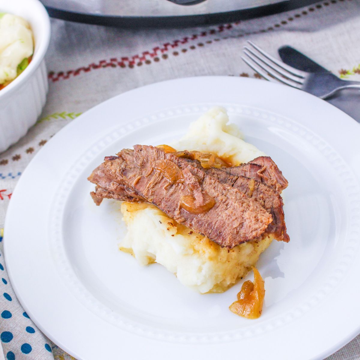 slices of flank steak and onions served over mashed potatoes