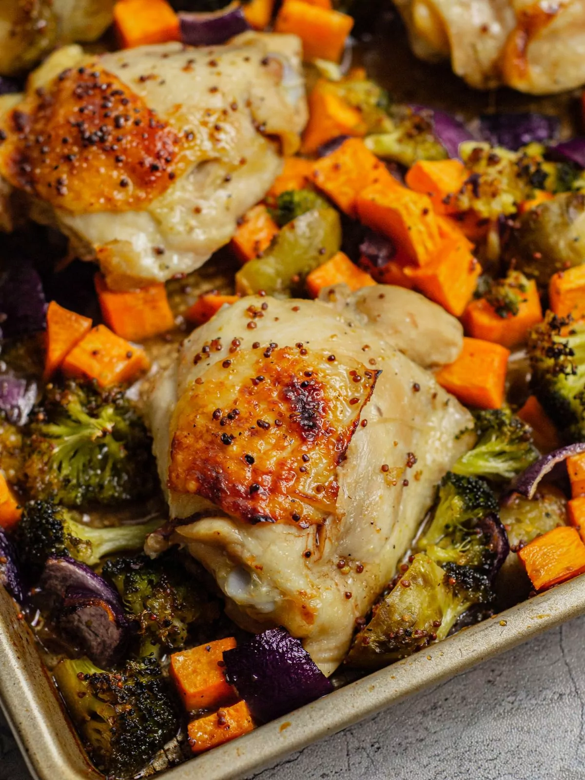 close up of the baked chicken thighs and veggies on a sheet pan