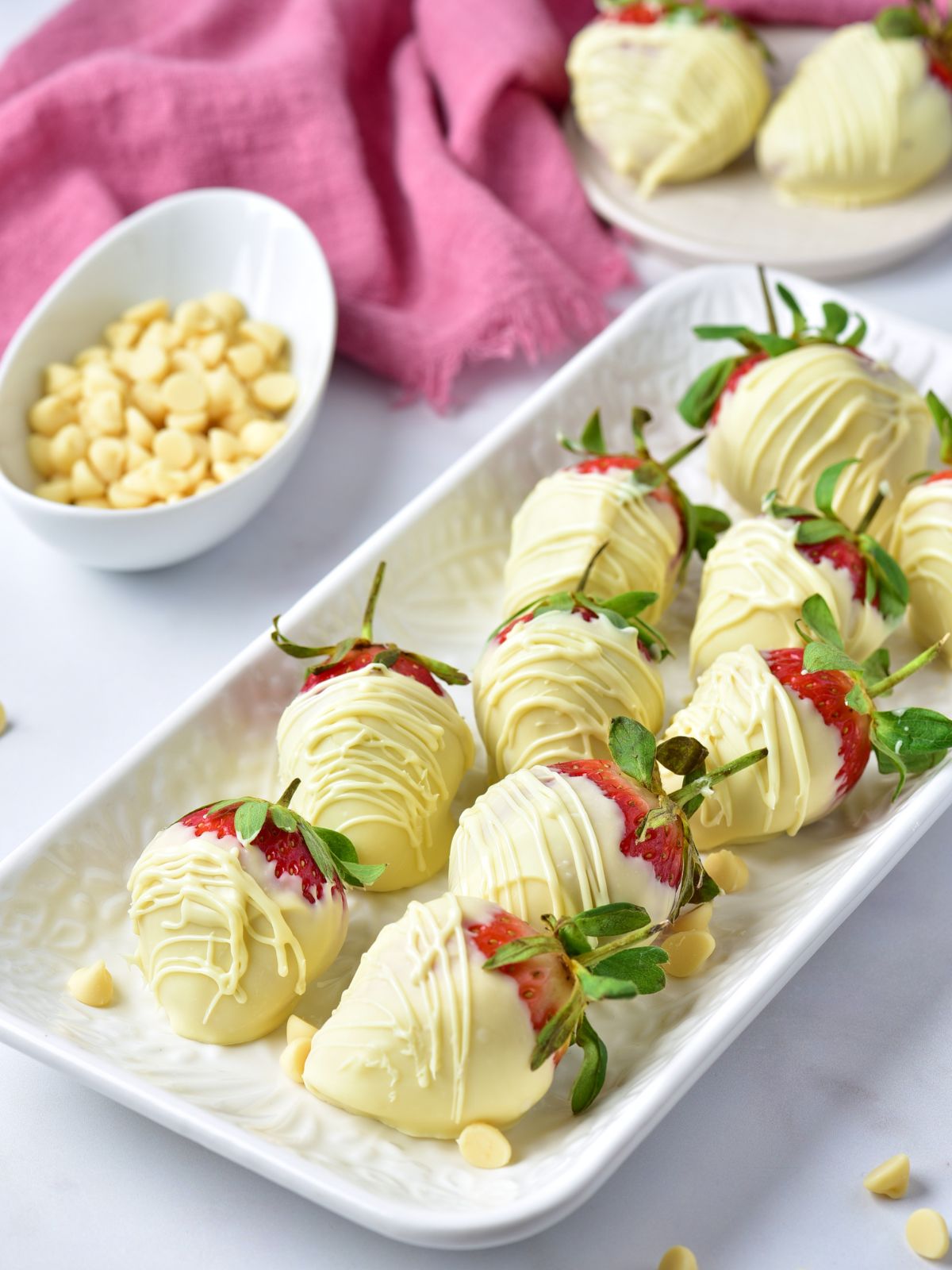 rectangle platter filled with White Chocolate Covered Strawberries with a pink cloth in the background