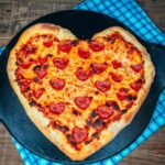 heart shaped pizza on pizza stone.