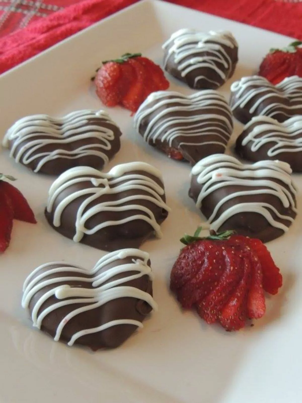 plate of chocolate covered strawberries with white chocolate drizzle.