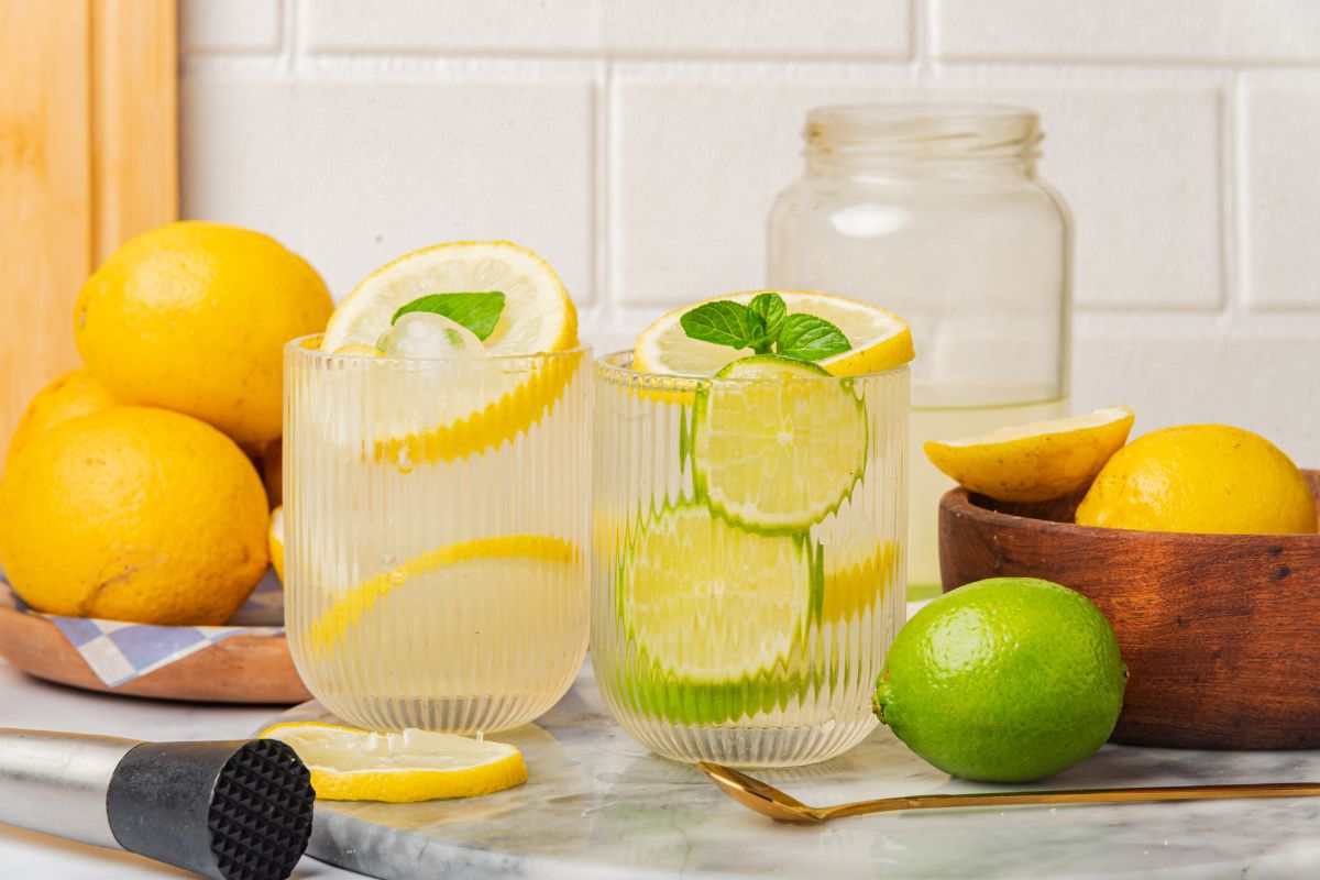 two ribbed glasses filled with water flavored with lemon and lime slices and fresh mint