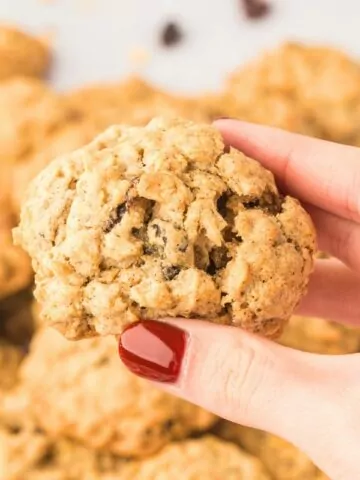 oatmeal cookies being held in hand with red nail polish.