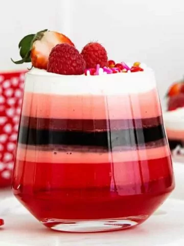 cup of red jello with strawberries and raspberries.