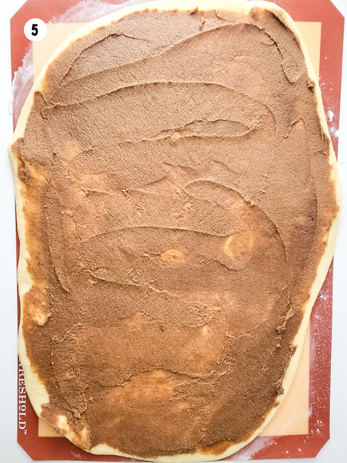 cinnamon sugar mixture spread on top of dough rolled out into a rectangle
