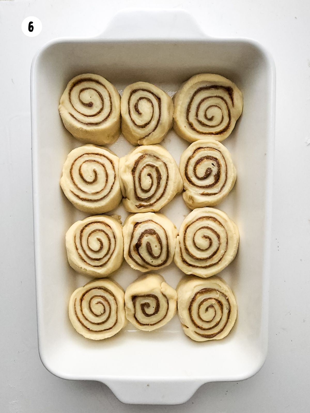 sliced cinnamon rolls added to a white baking dish