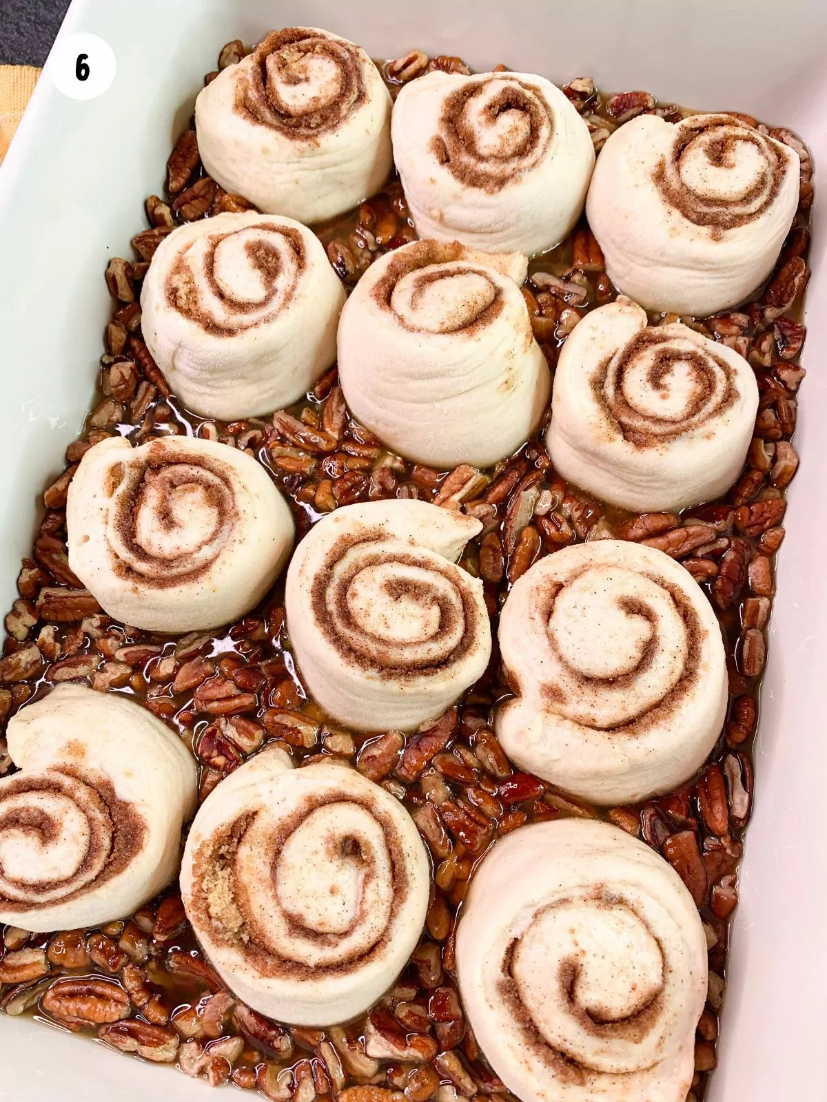 cinnamon rolls placed on top of the pecans and sauce