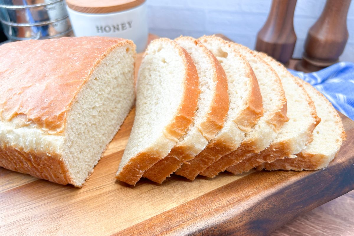 loaf of white sandwich bread sliced on a wood board