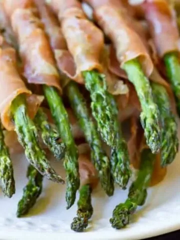 prosciutto wrapped asparagus on white plate MSN.