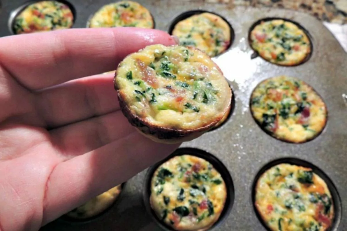 mini quiche in muffin pan and one being held in hand closeup.