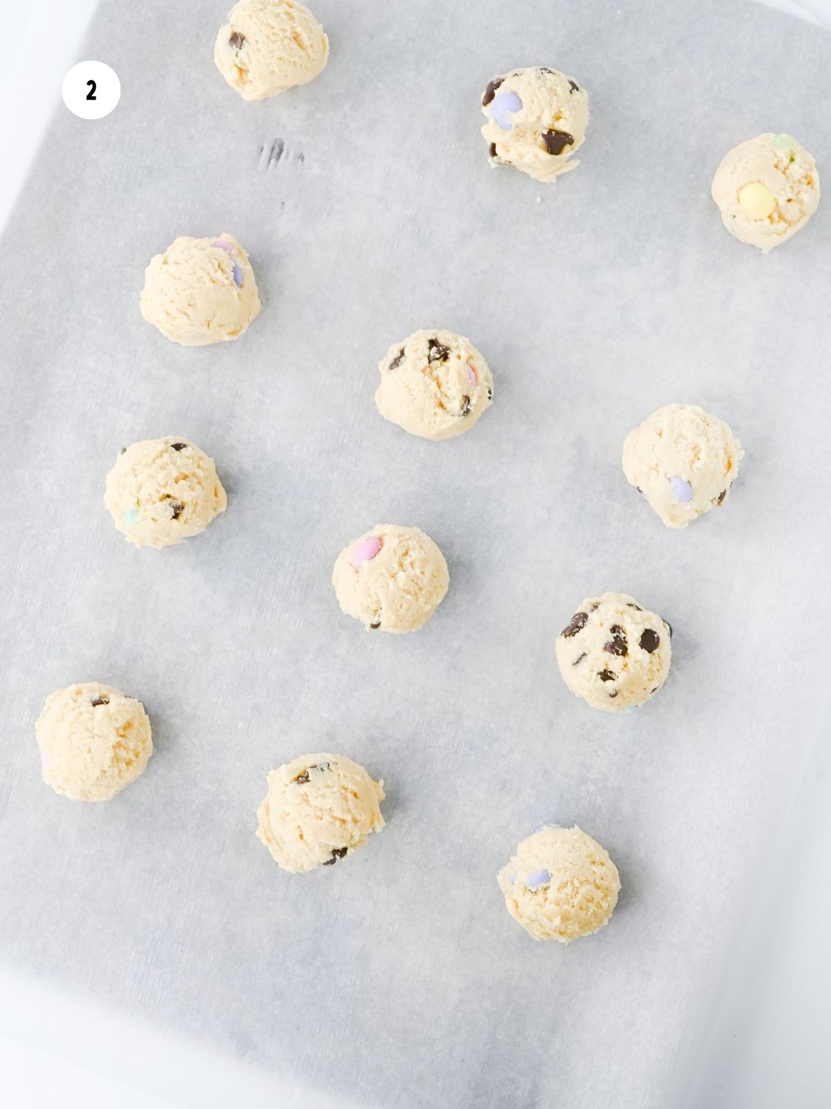 cookie dough balls on a parchment lined baking sheet