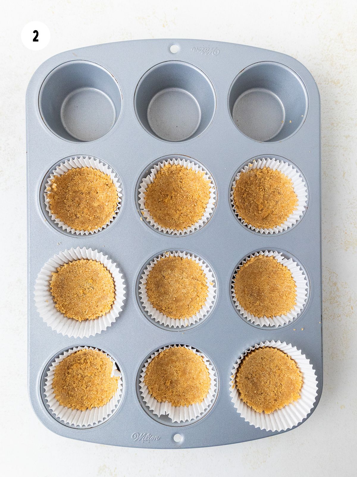 graham cracker crust pressed into the bottom of 9 liners placed in a muffin pan.
