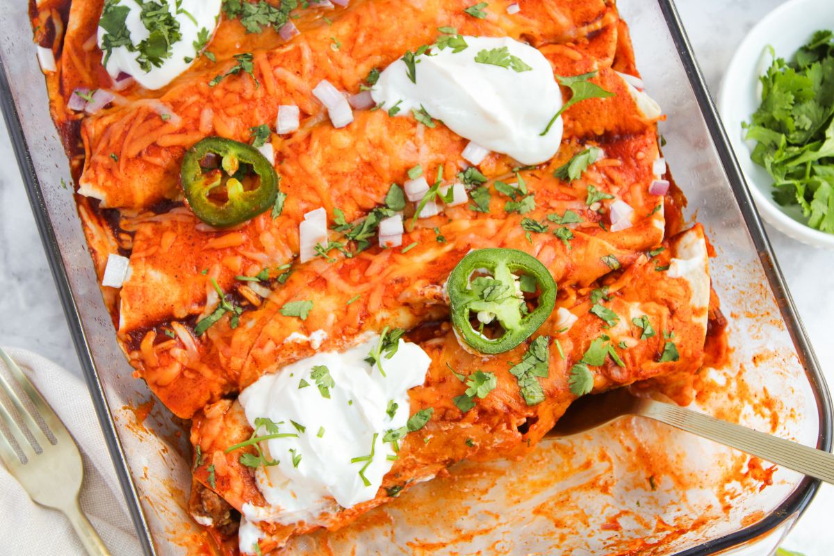 baking dish filled with Cheesy Beef Enchiladas with toppings.