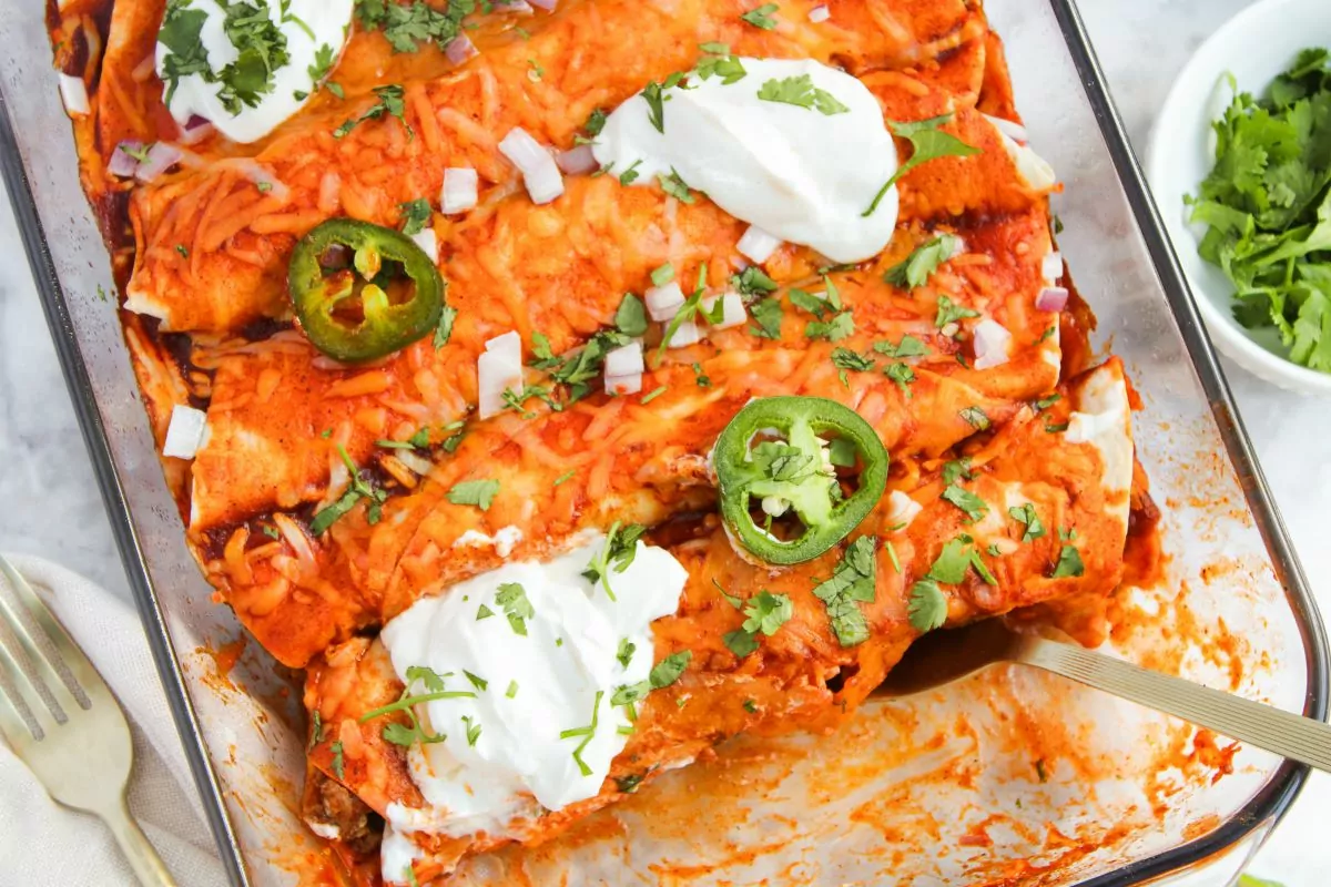 baking dish filled with Cheesy Beef Enchiladas with toppings.