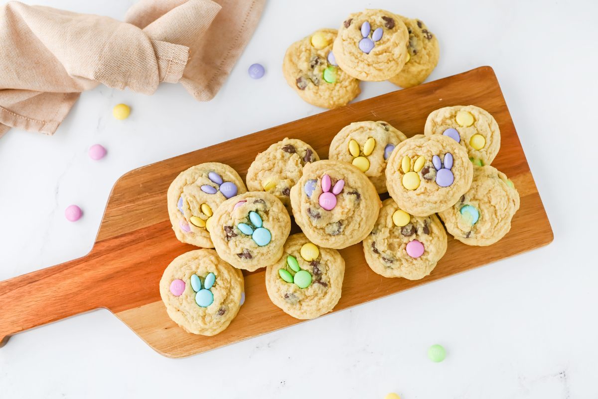 wooden board filled with chocolate chip cookies and pastel M&M's that make bunnies