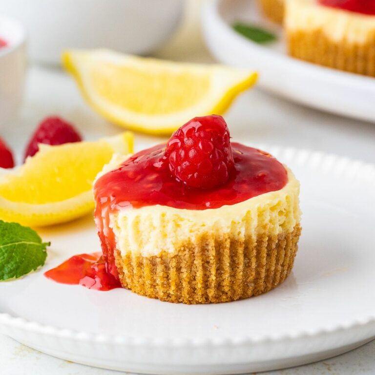 Mini Cheesecakes topped with raspberry sauce. Lemon slices in the background