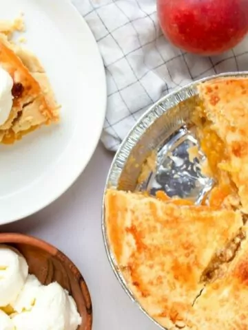 slice of peach pie on plate with full pie in pie plate. Bowl of ice cream to the side MSN.