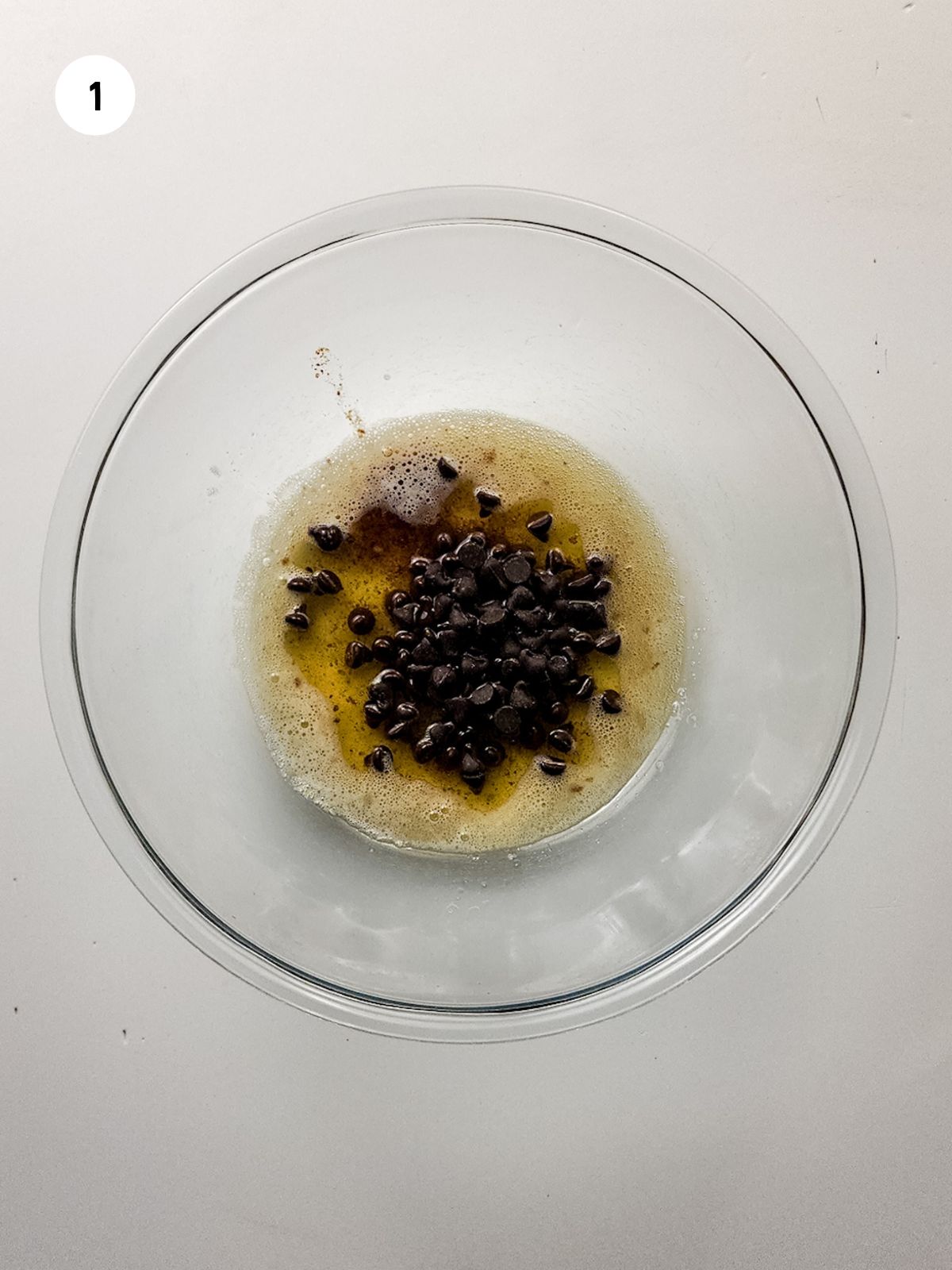 melted butter and chocolate chips in a clear mixing bowl