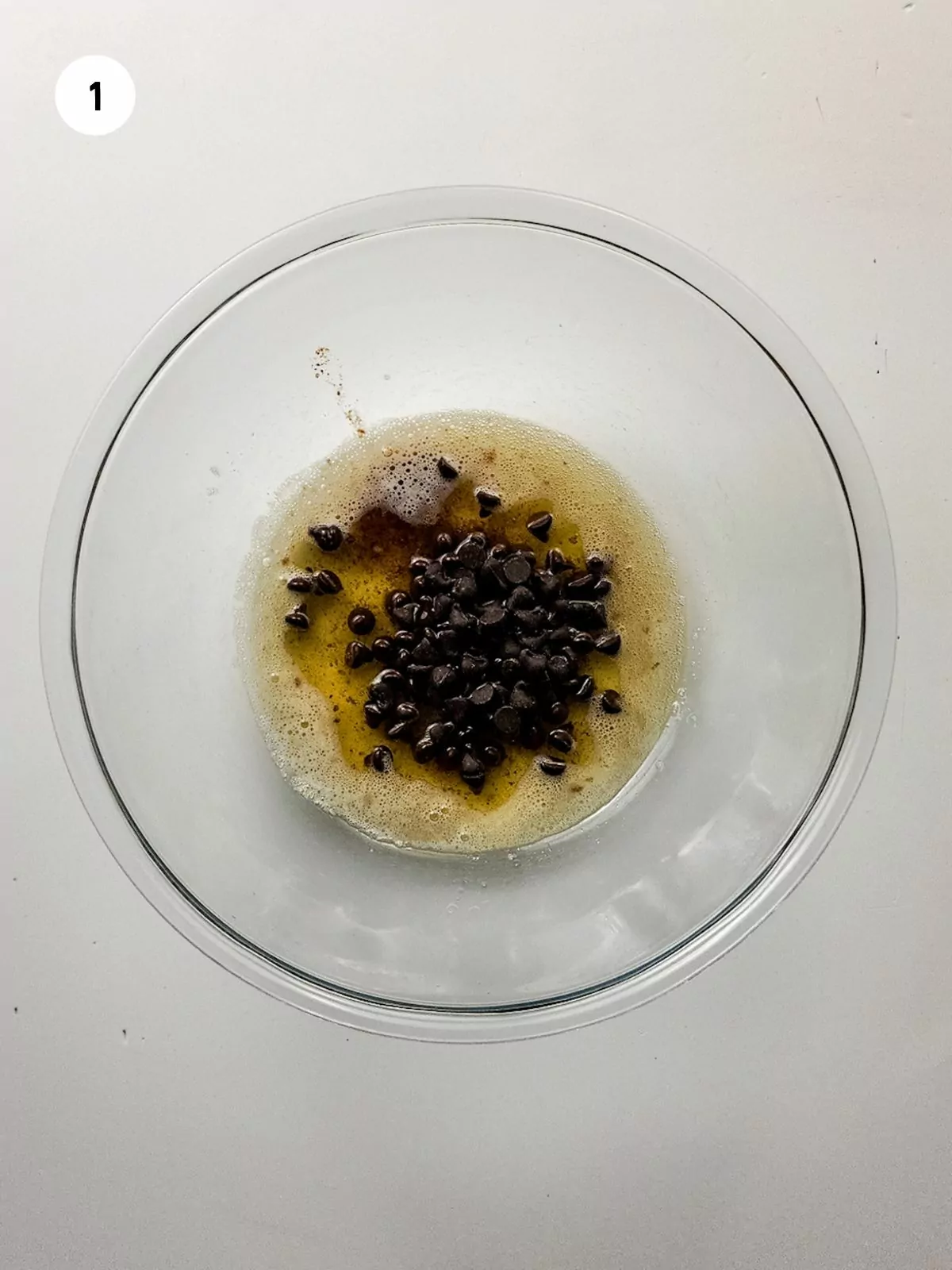 melted butter and chocolate chips in a clear mixing bowl