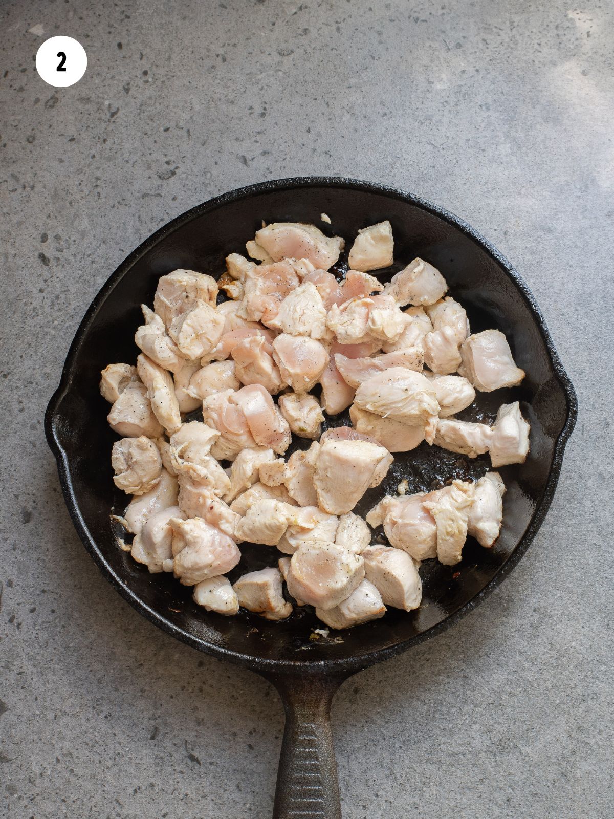 chicken cooking in a cast iron pan