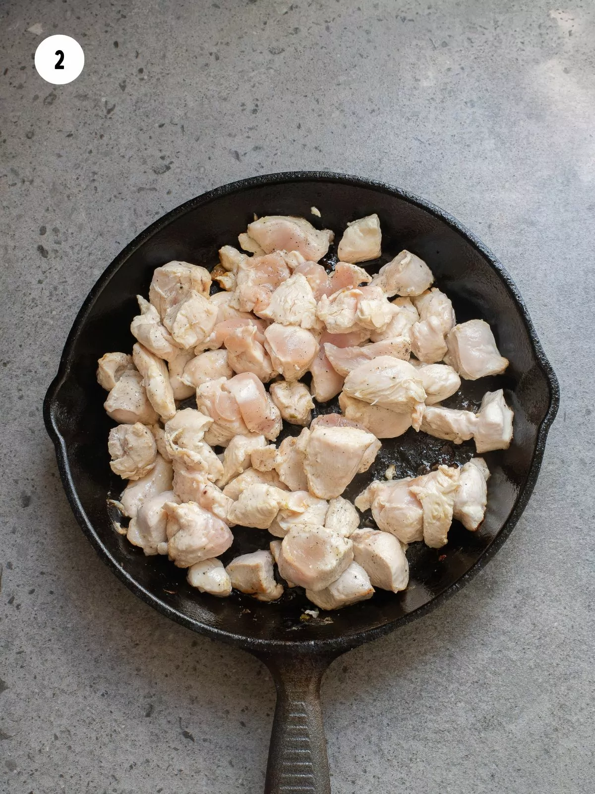 chicken cooking in a cast iron pan
