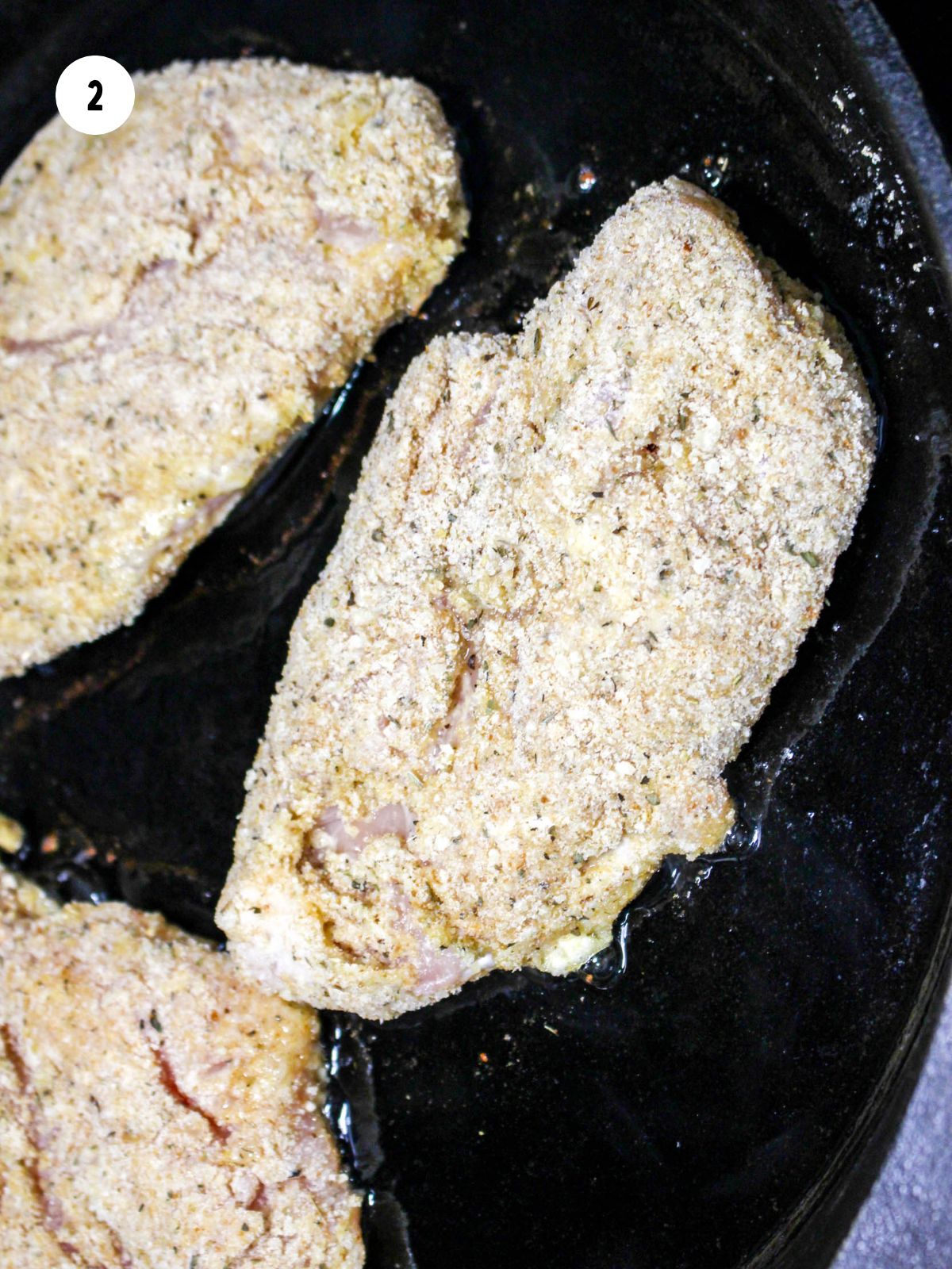 breaded chicken pan frying in a cast iron skillet