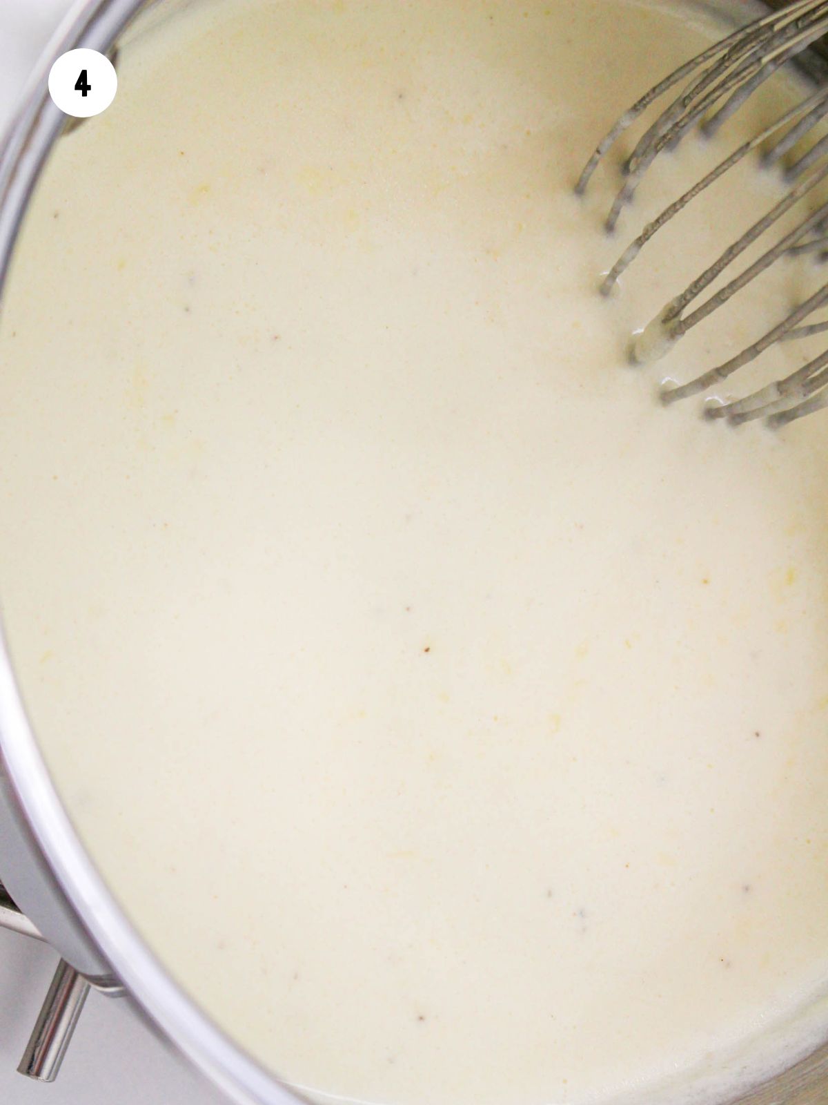 completed Alfredo sauce in a pan being whisked