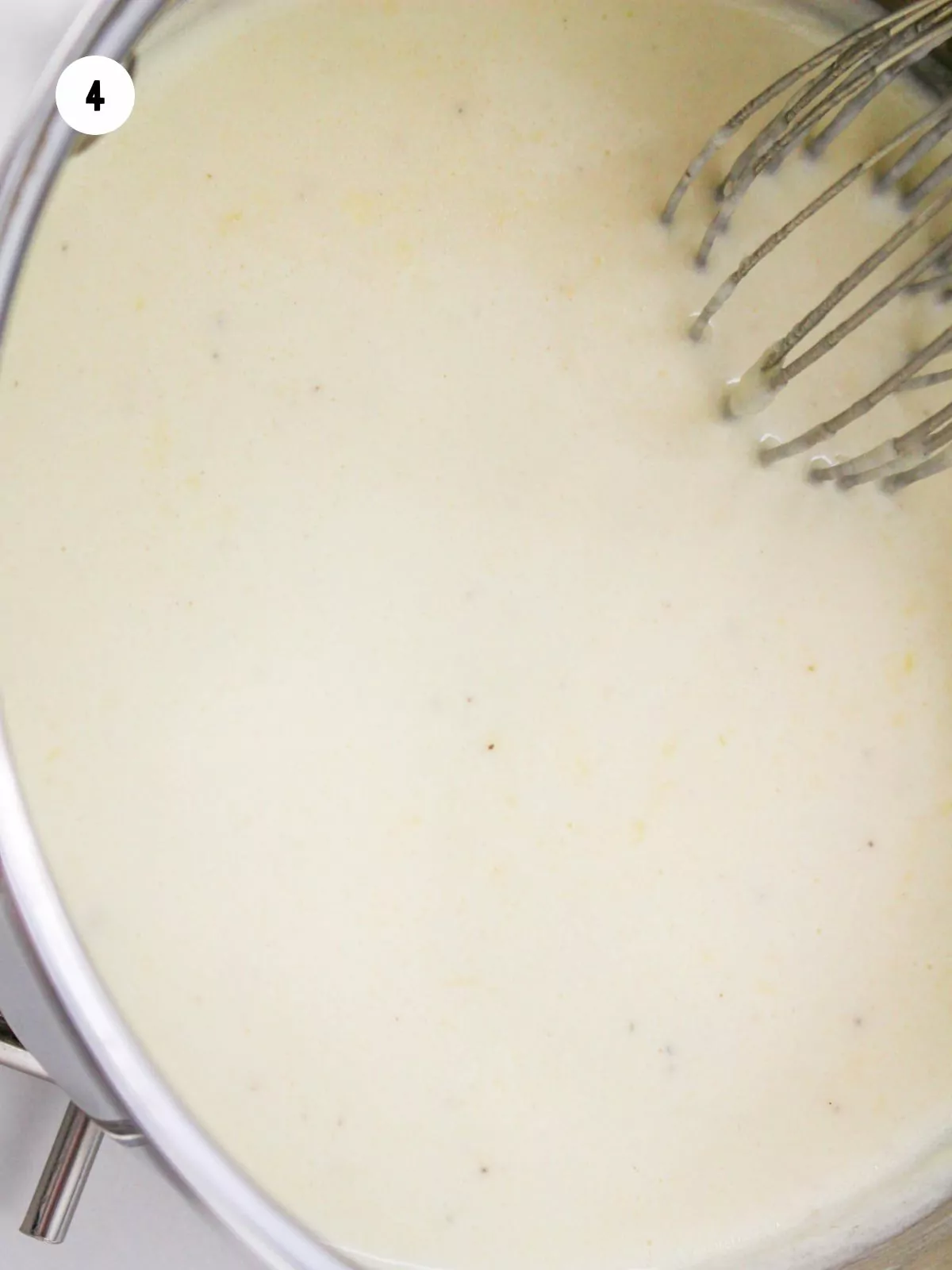completed Alfredo sauce in a pan being whisked