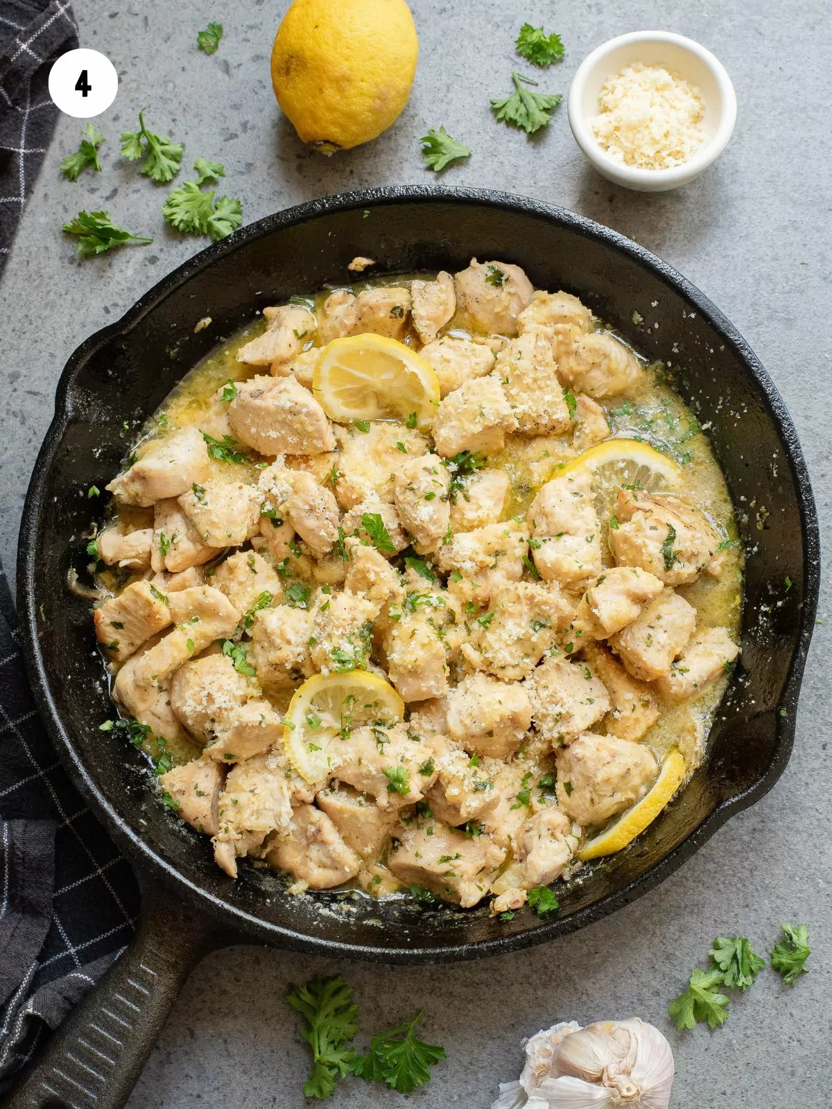 chicken in garlic butter sauce topped with parsley, parmesan and lemon