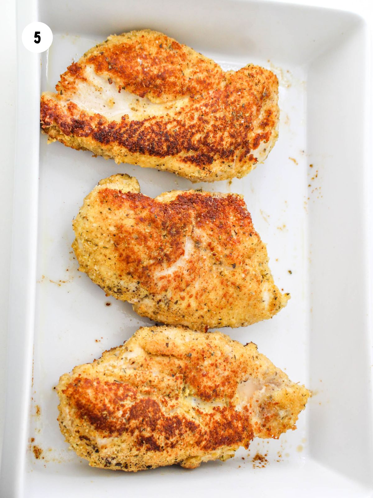 pan fried breaded chicken breasts in a white baking dish