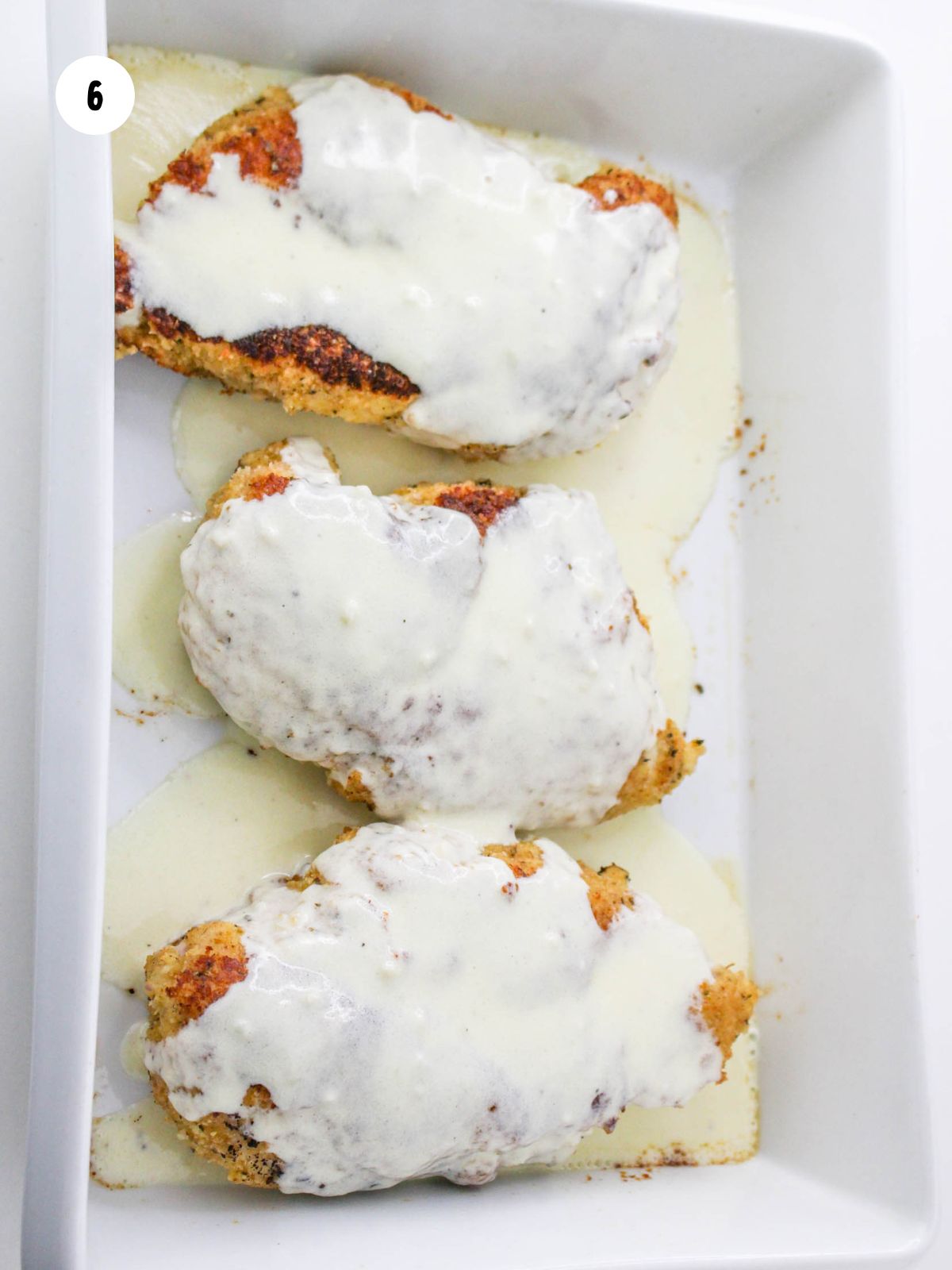 alfredo on breaded chicken in the baking dish