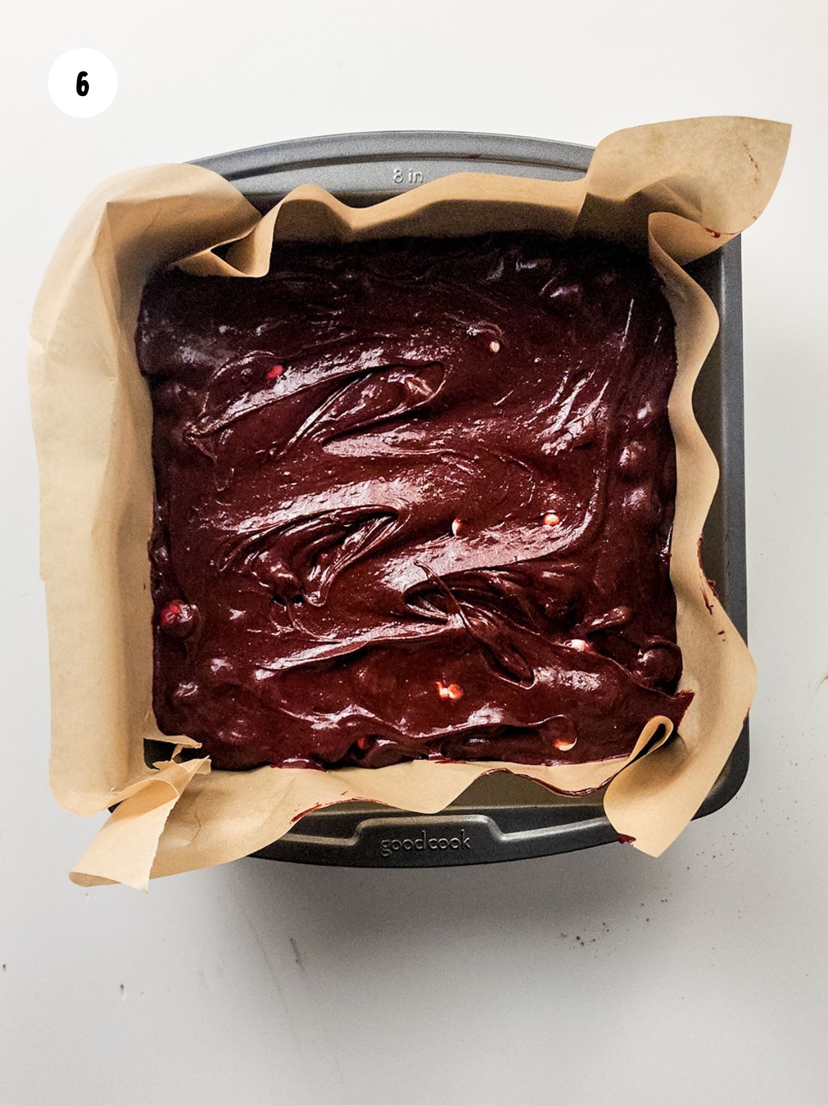 brownie batter added to a pan lined with parchment paper