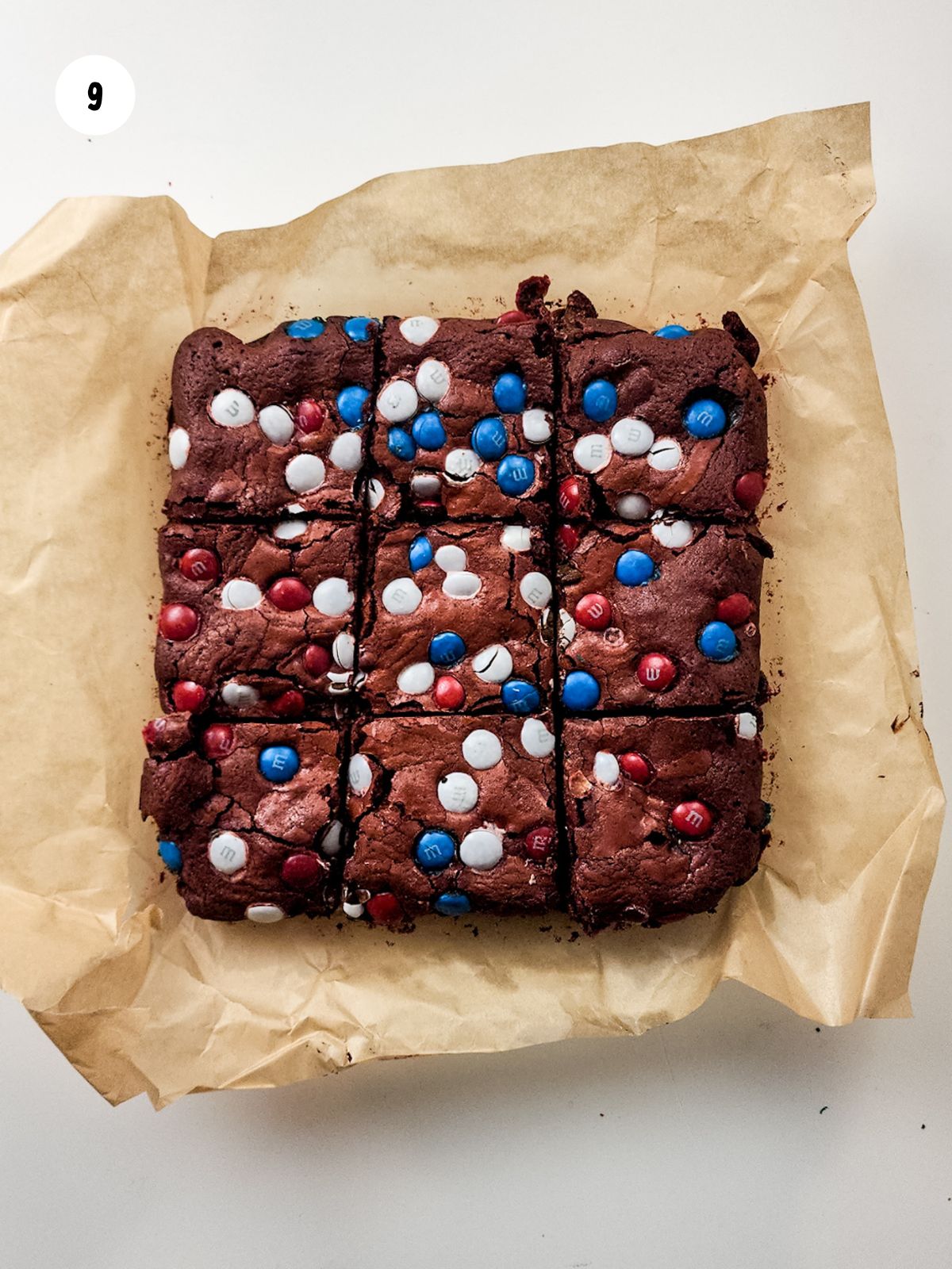 brownies sliced into squares on the parchment paper