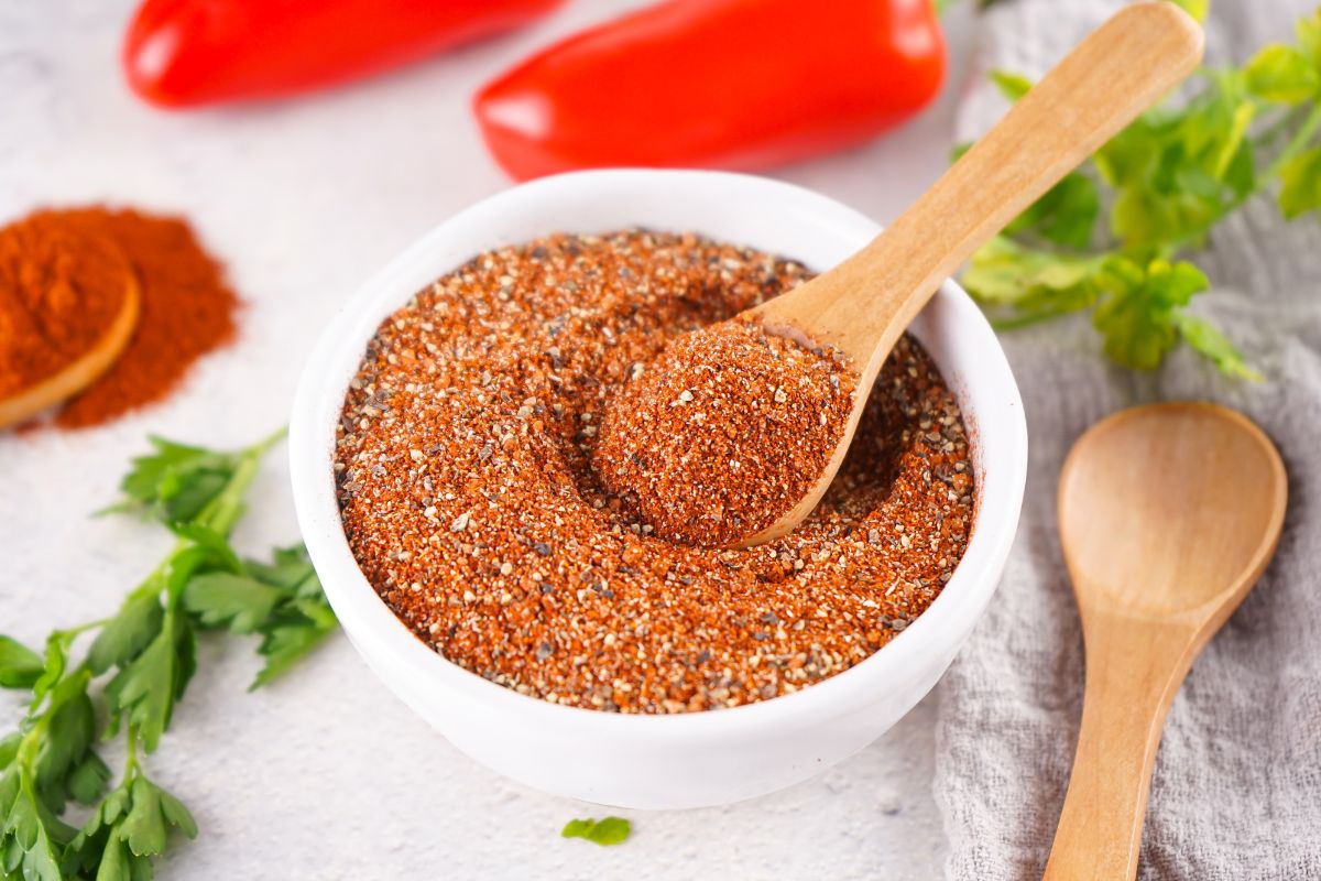 BBQ Seasoning Mix in a small white bowl. A small wooden spoon is dipped into the seasoning