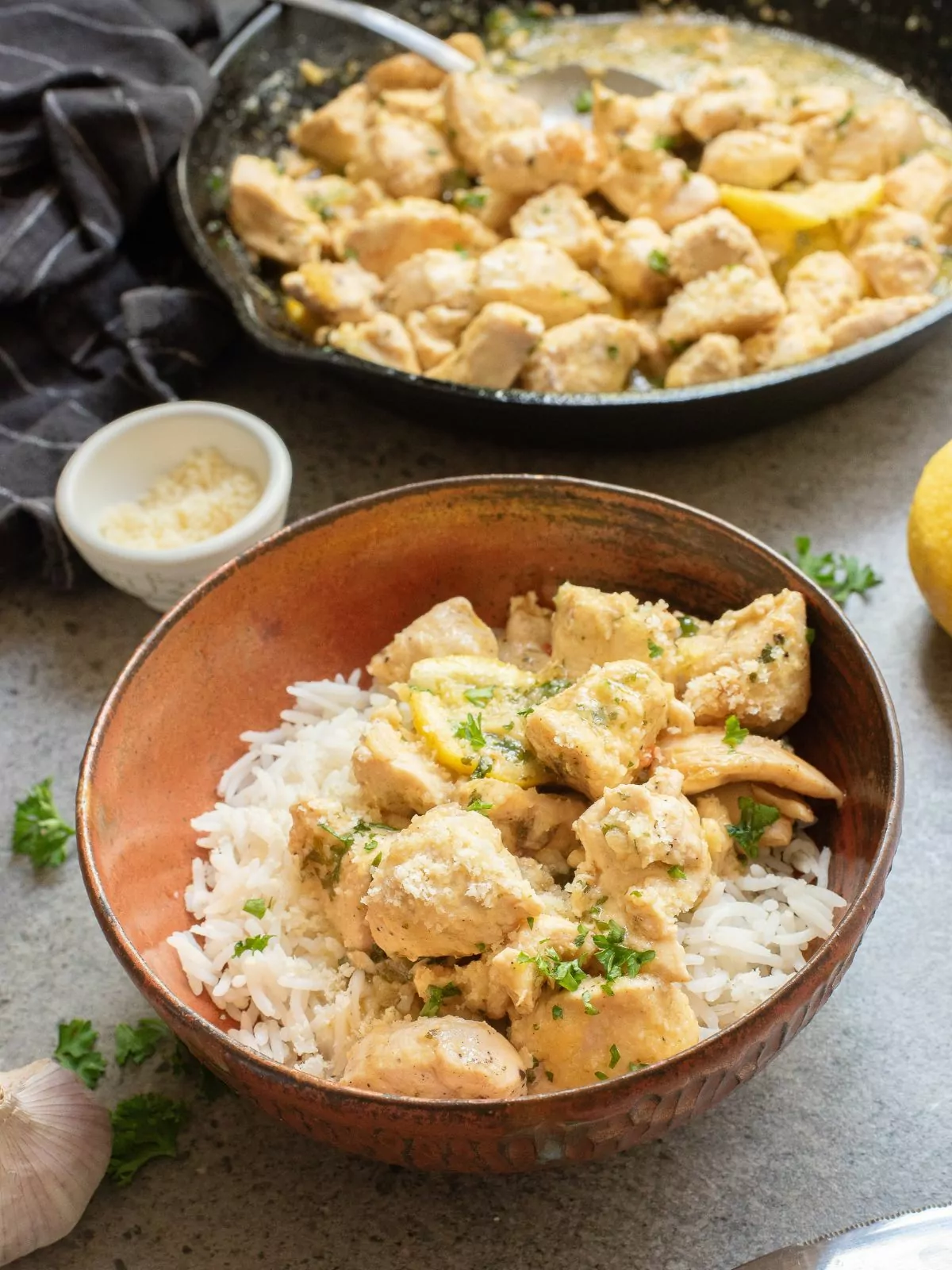 Garlic Chicken Bites served over rice and a cast iron pan with the chicken bites in the background