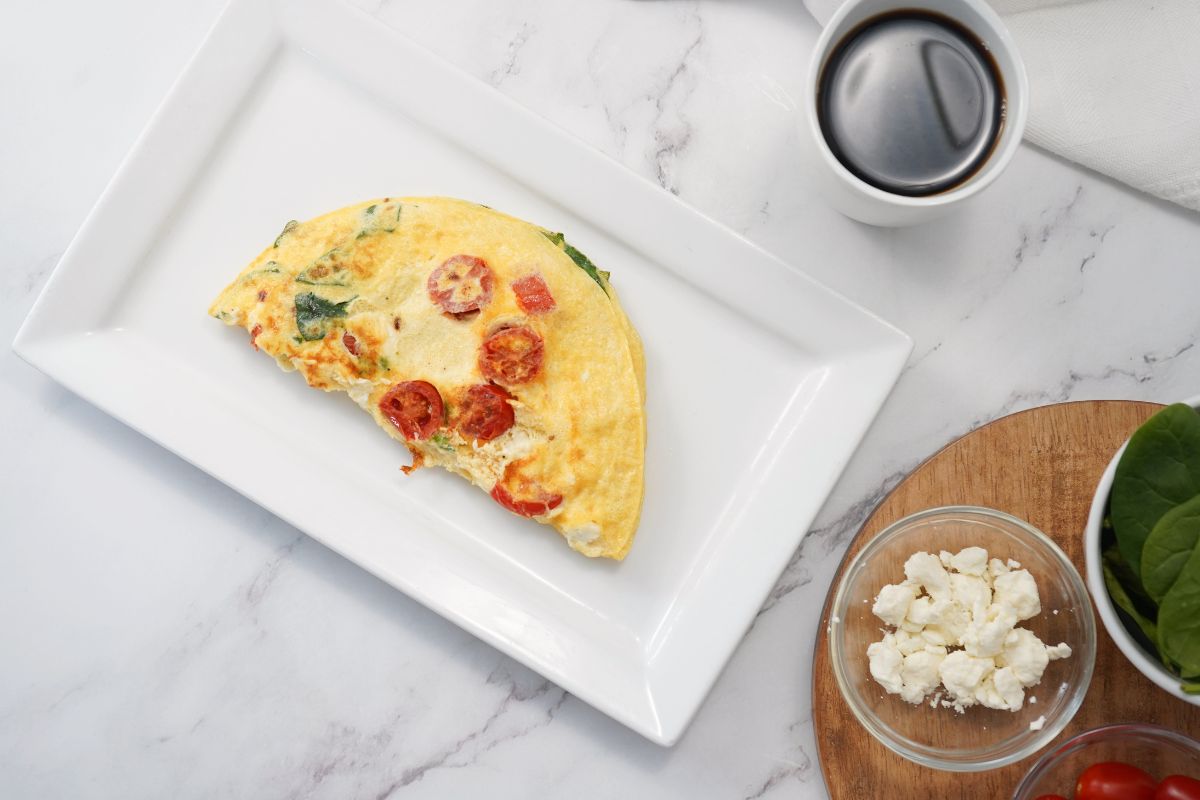 Mediterranean Omelette on a rectangle platter. On the side is a cup of coffee and filling ingredients