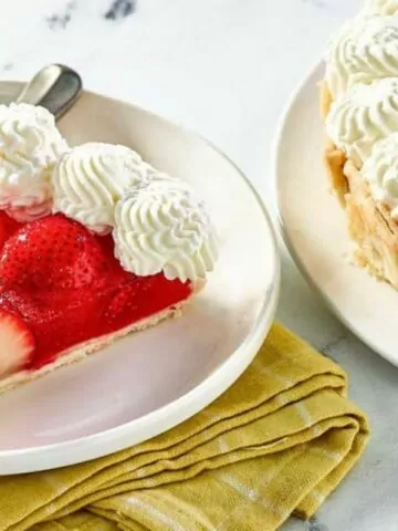 slice of strawberry pie with whipped cream with full pie in background MSN.