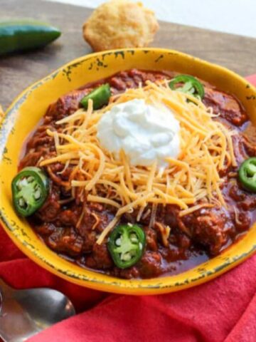 bowl of chili with jalapenos and corn muffins.