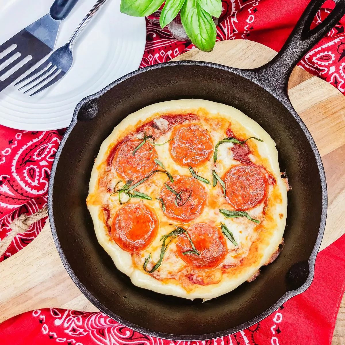 pepperoni pizza made in a cast iron pan on cutting board.