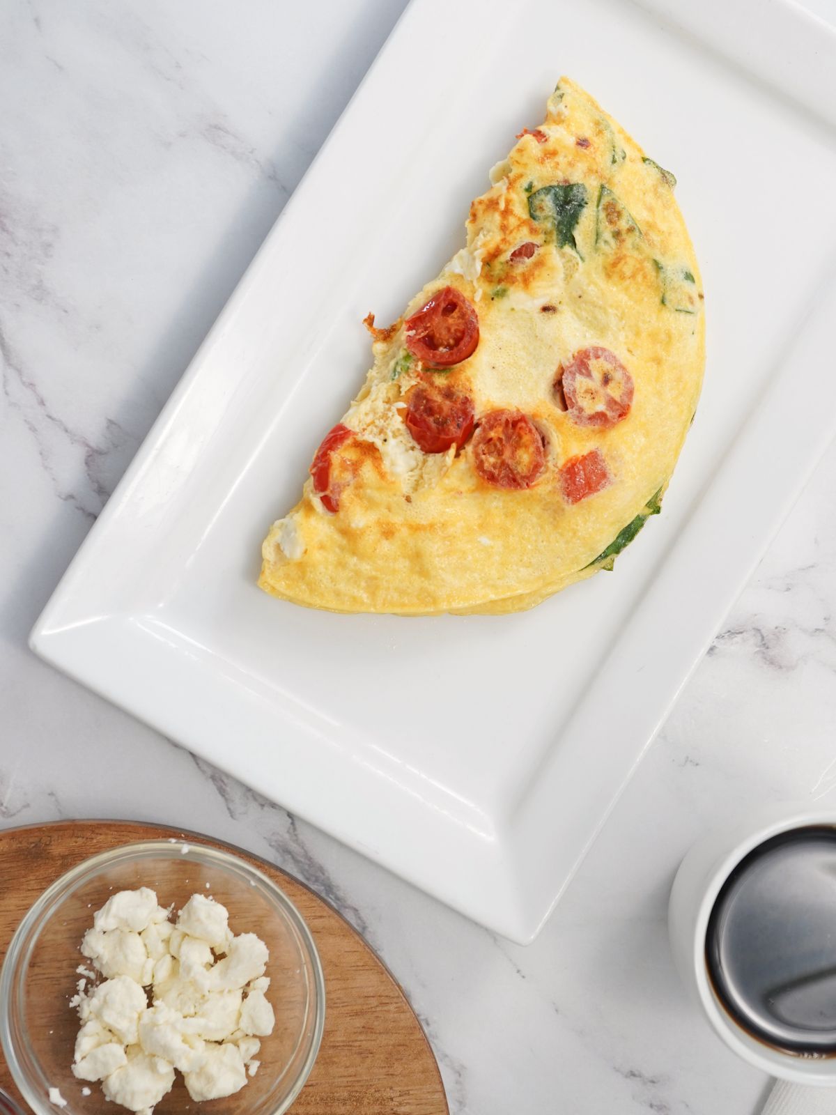 Mediterranean Omelette with a bowl of feta and cup of coffee at the bottom of the photo