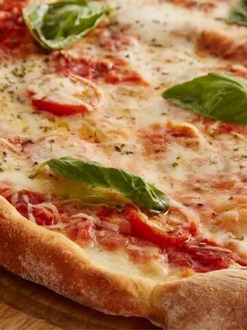 homemade pizza with basil leaves on wooden tray MSN.