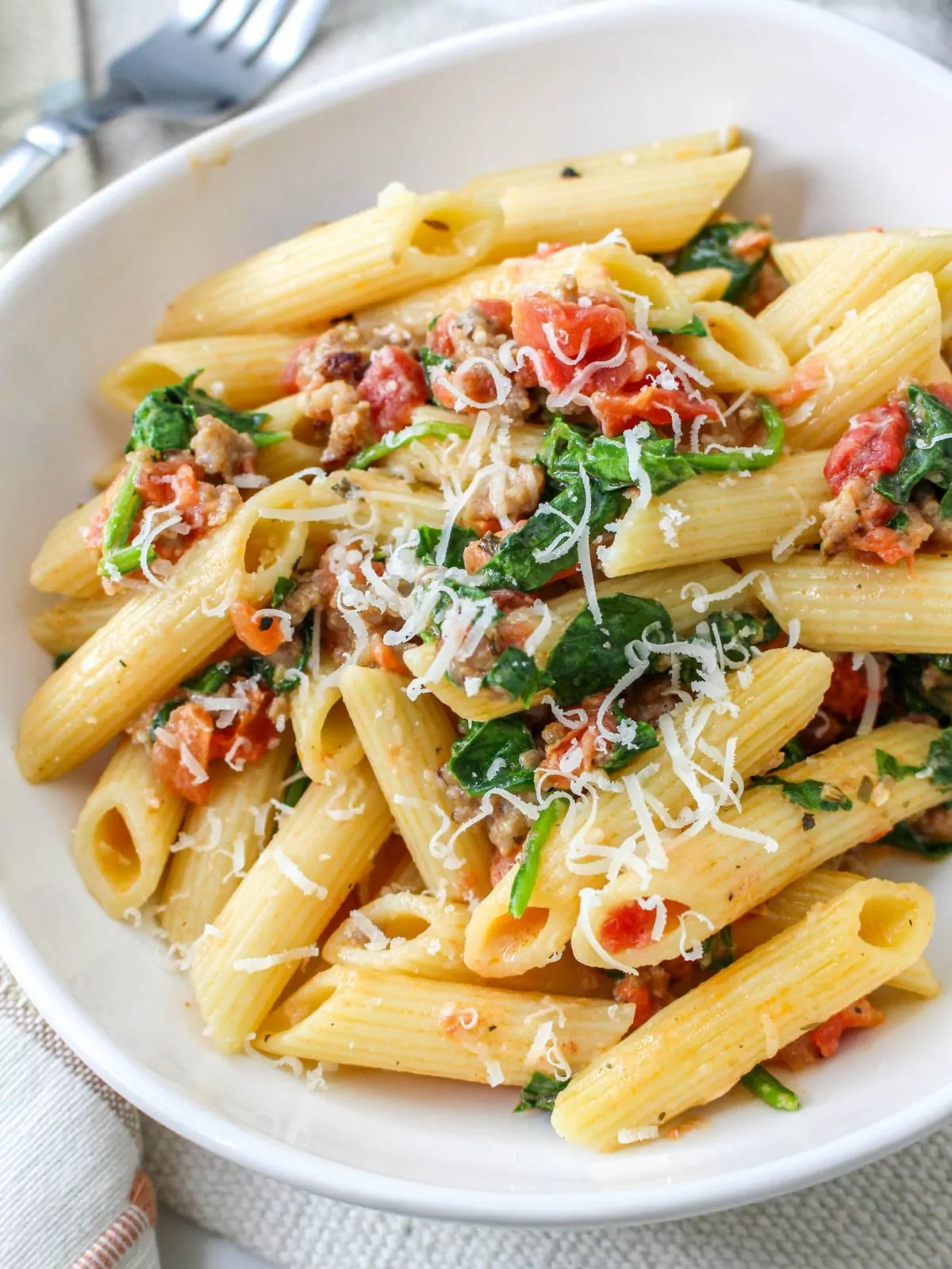 Creamy Sausage Pasta with Spinach served in a shallow white bowl