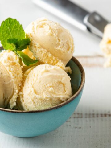 vanilla ice cream in blue bowl with sprig of mint.