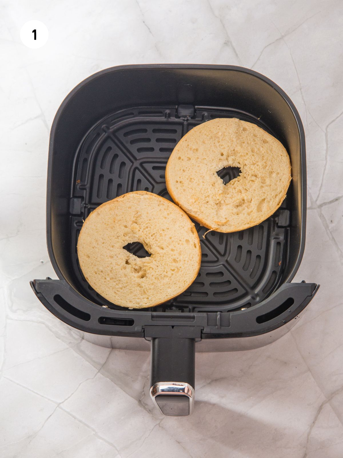 Bagel halves in the air fryer basket.