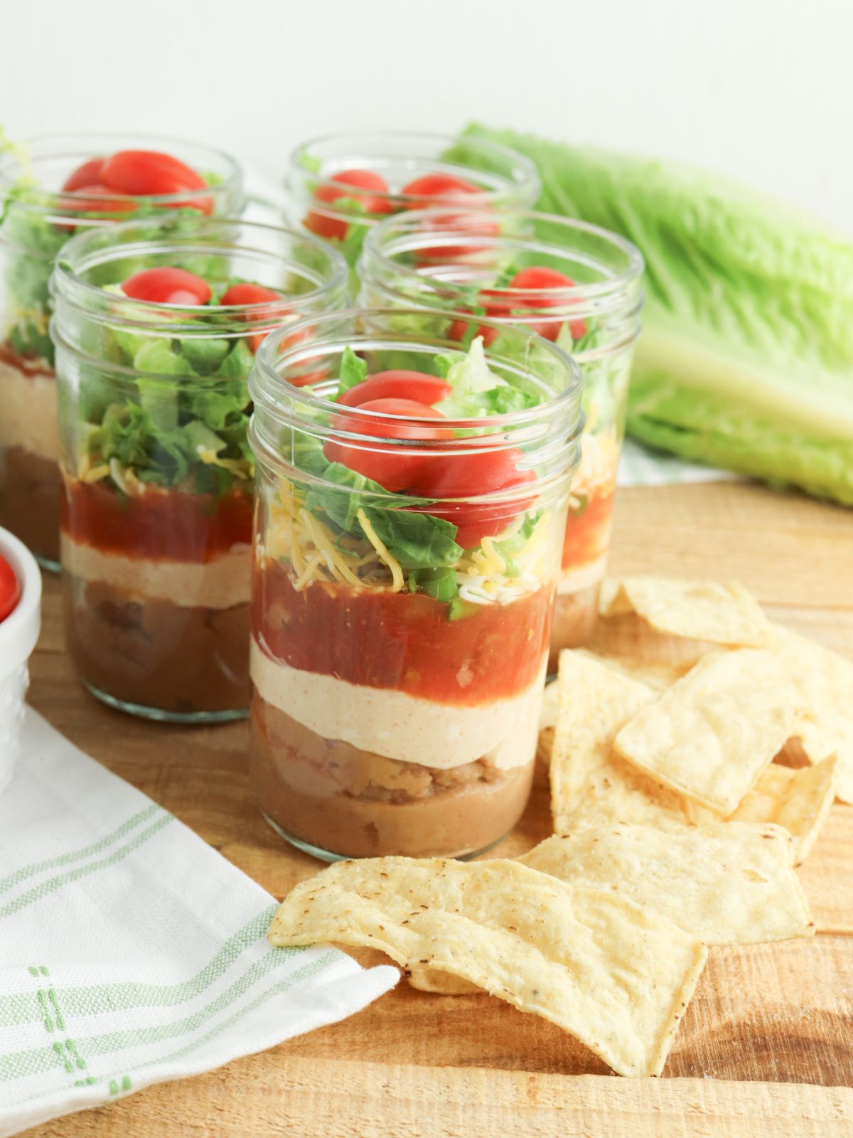 Mason Jar Taco Layered Dip with tortilla chips on the side.