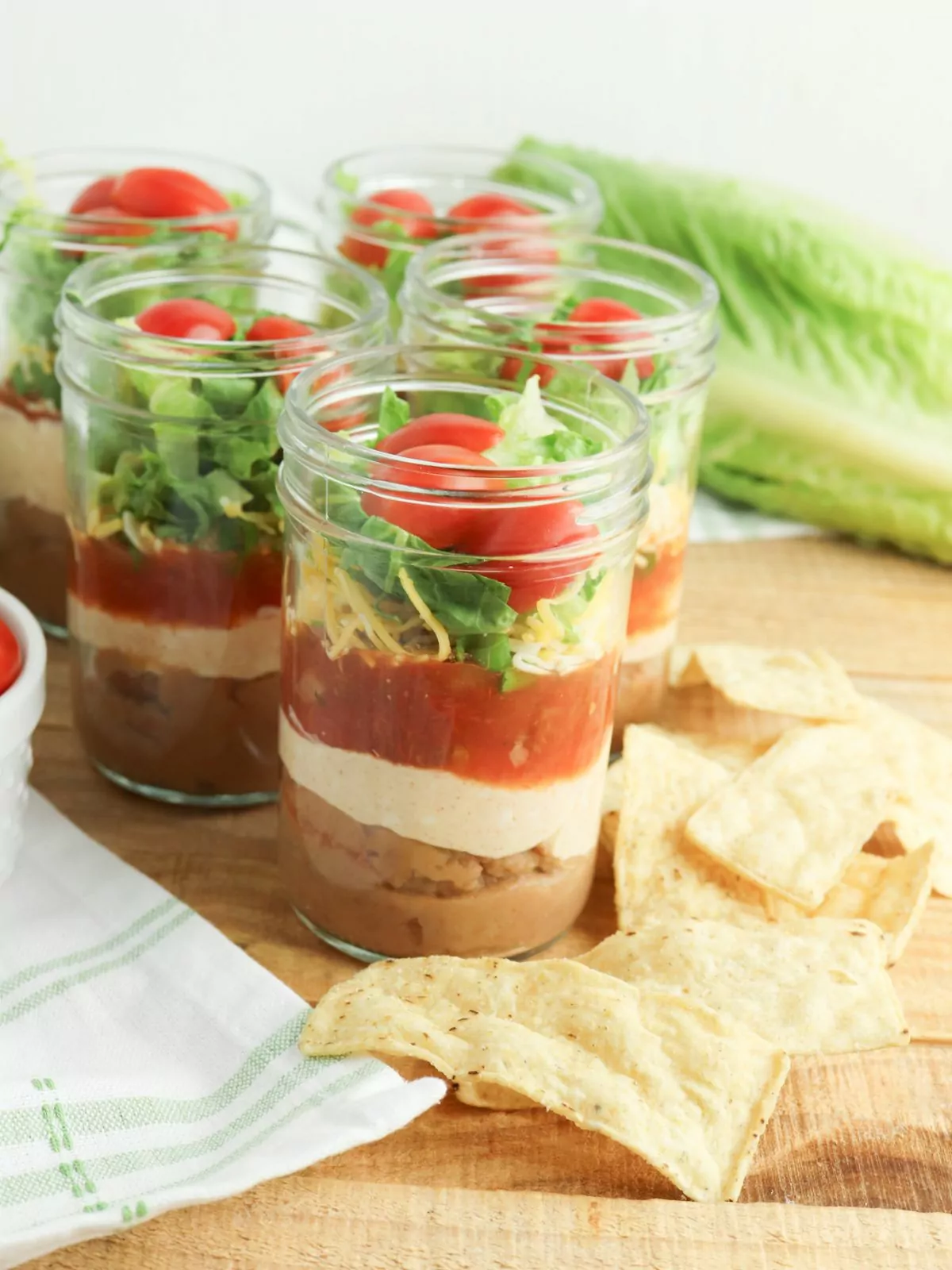 Mason Jar Taco Layered Dip with tortilla chips on the side.