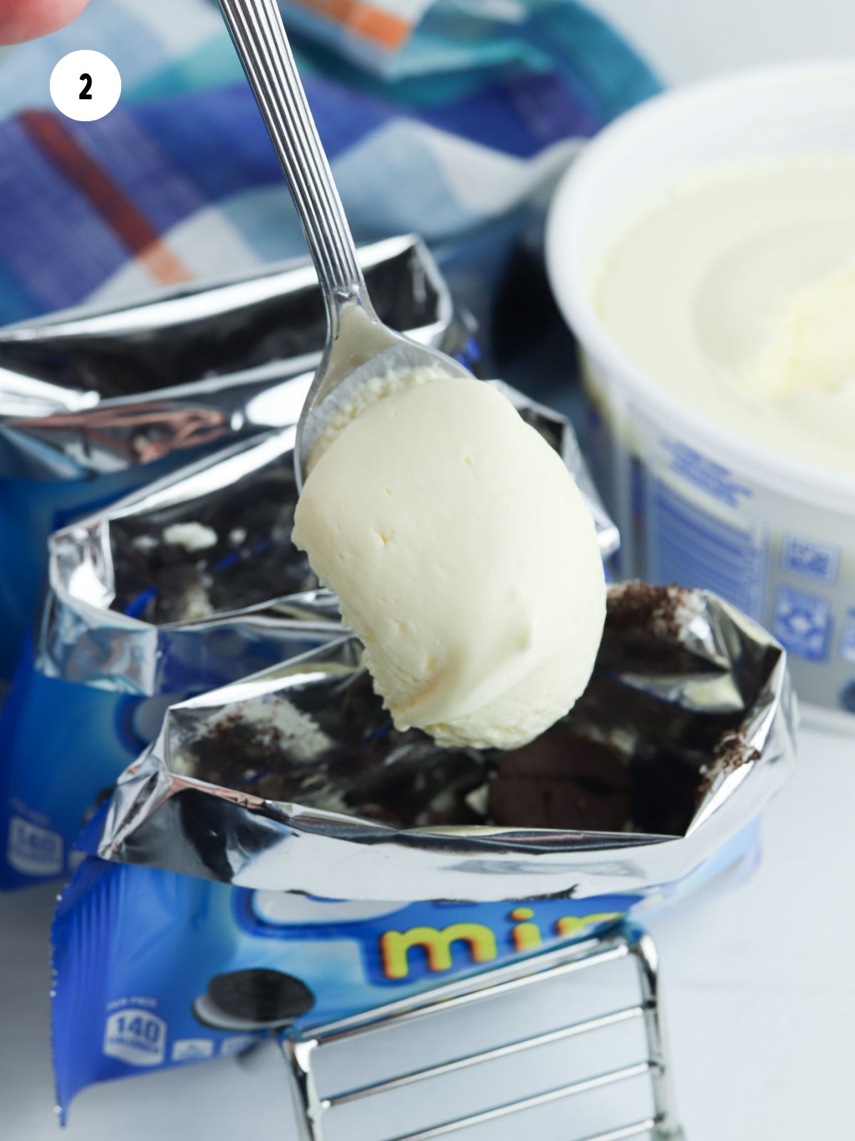 spoonful of cheesecake filling being put into the bag of crushed oreos