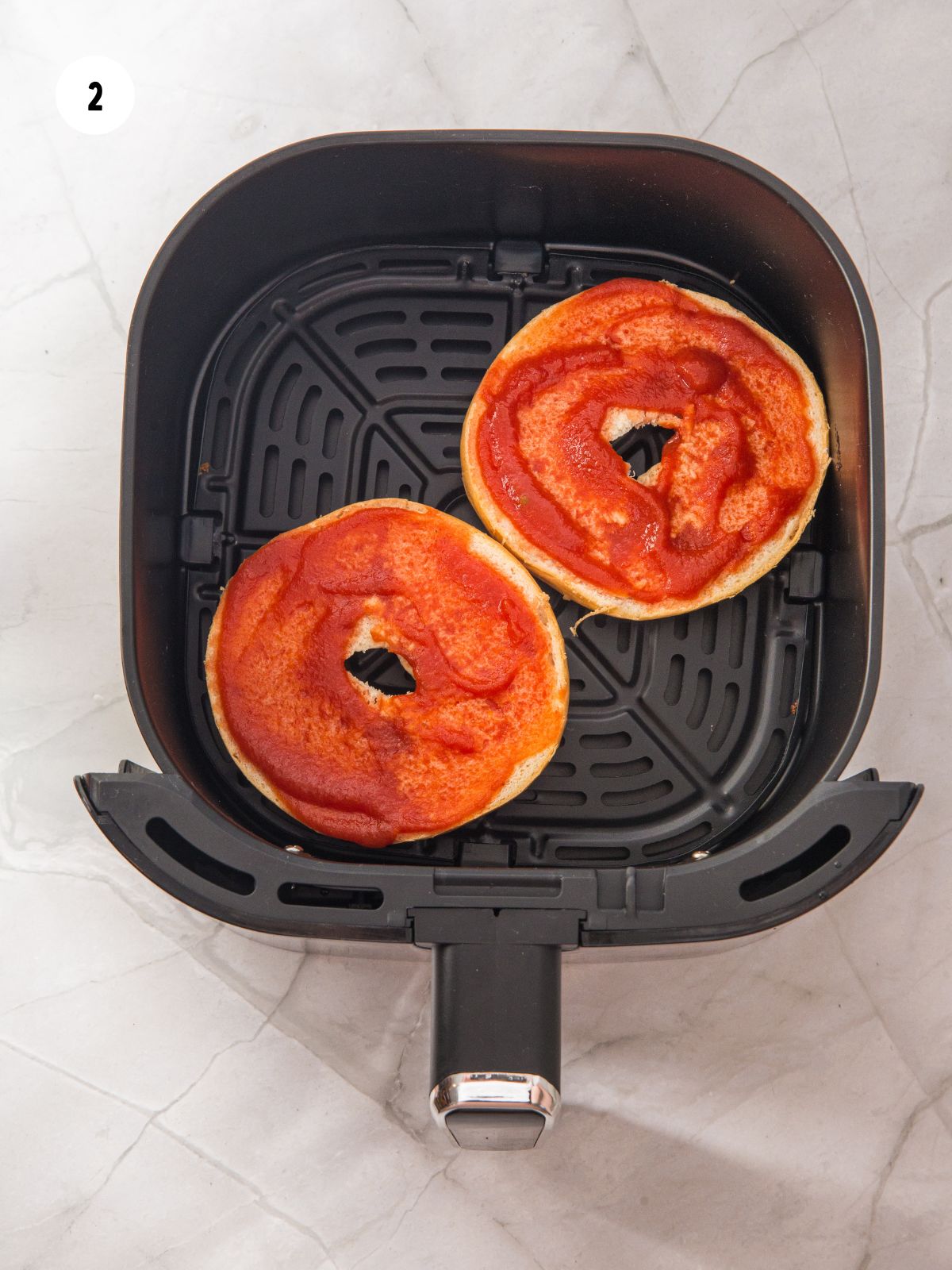 Bagel halves topped with pizza sauce.